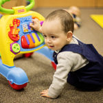 a boy sits beside a standing toy looking away