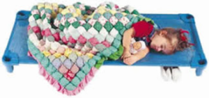 a girl sleeps on a blue cot, a colorful quilt is tucked around her