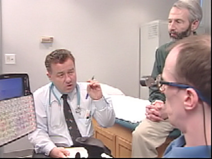 A doctor speaks with an individual with cerebral palsy and his personal care assistant.