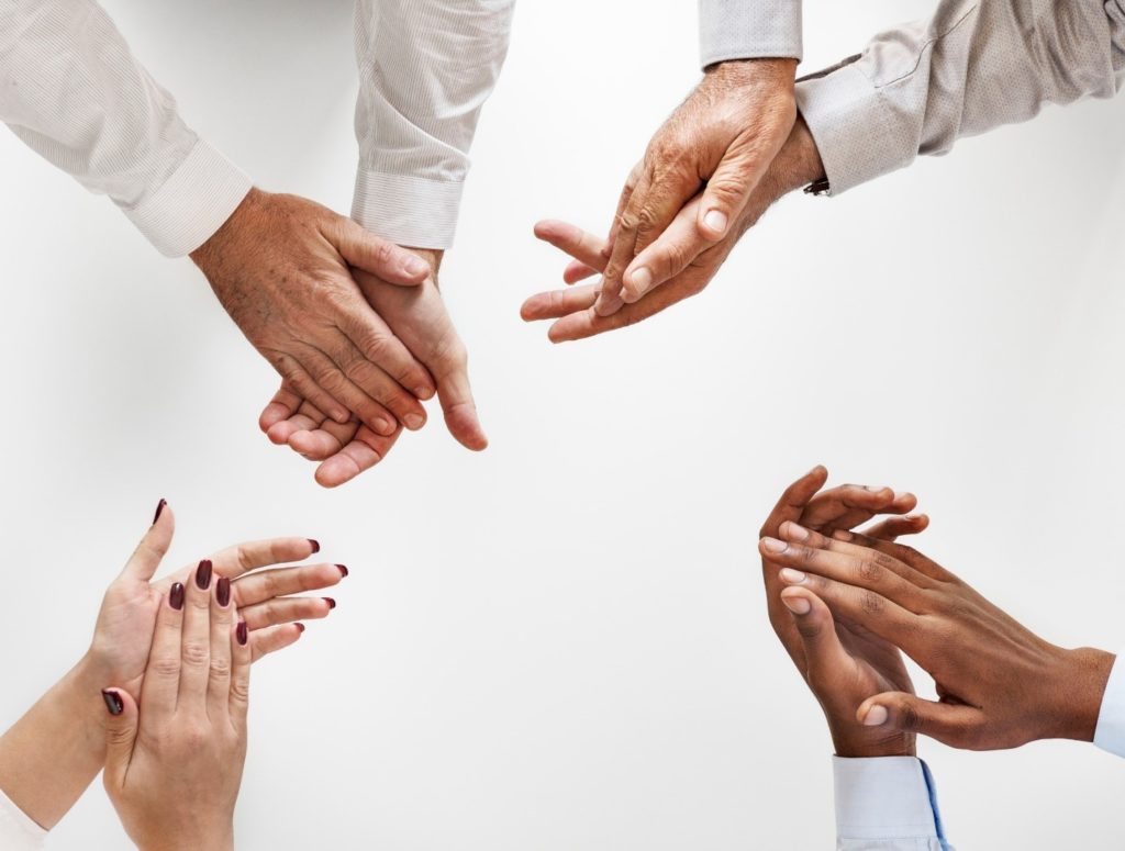 image of four sets of hands clapping