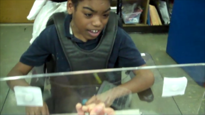 A student is using an acrylic board to work through a math problem.