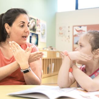 Teacher and child at a table using sign language.