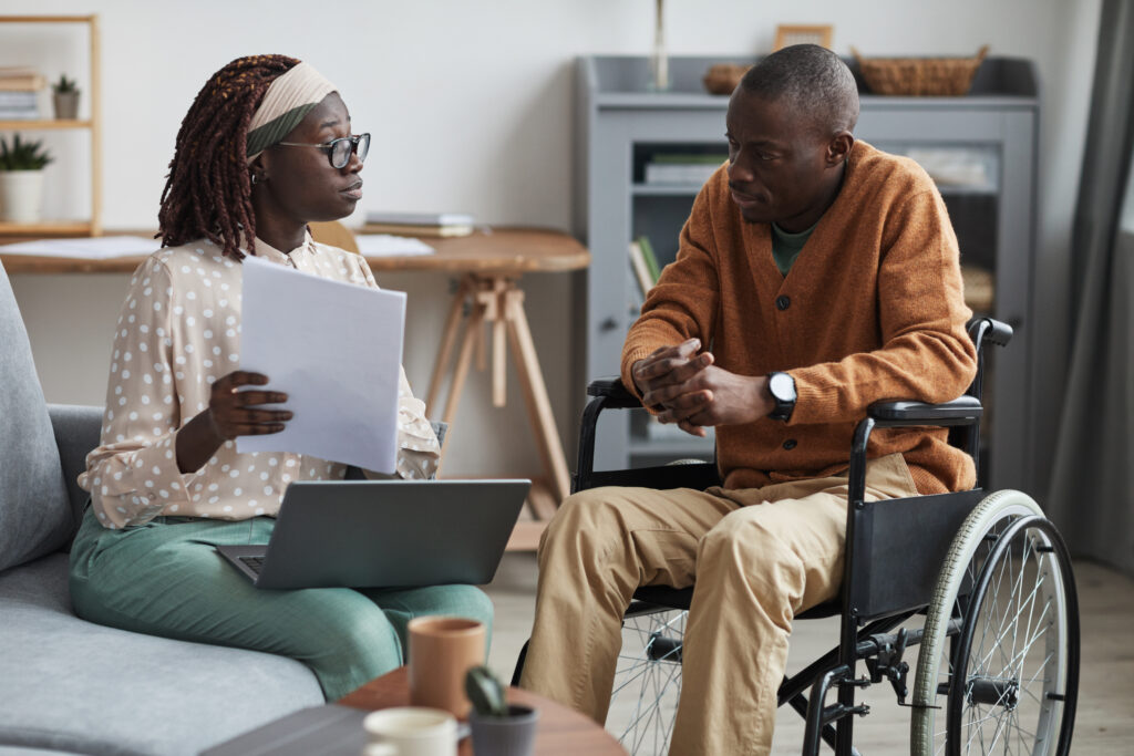 Portrait of African-American couple with handicapped man using wheelchair discussing papers