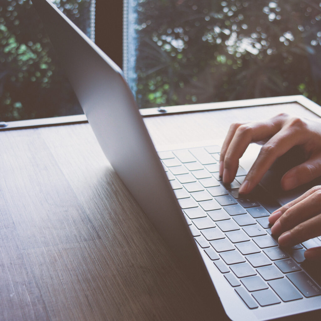 Computer laptop with blank screen on wood table, man hand typing computer at home