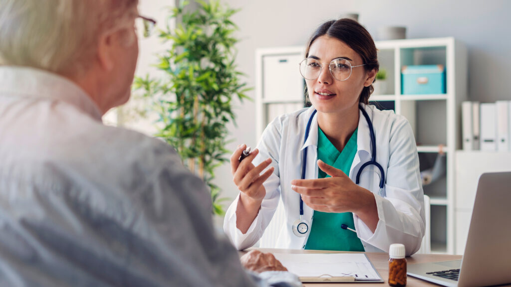 Doctor sitting at a table talking to a man.
