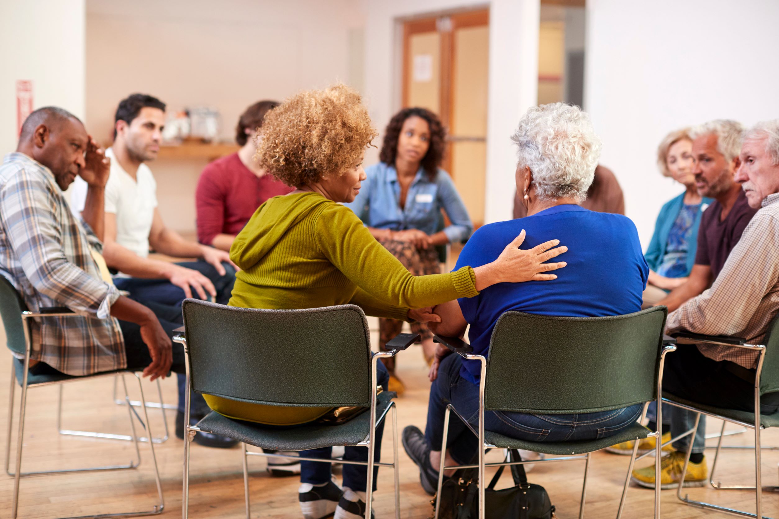 Group of adults sitting in chairs in a circle.
