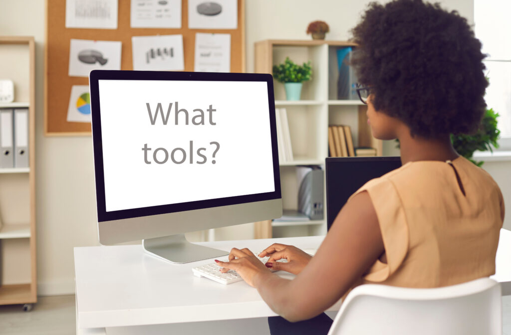 Black businesswoman sitting at office desk with what tools on screen