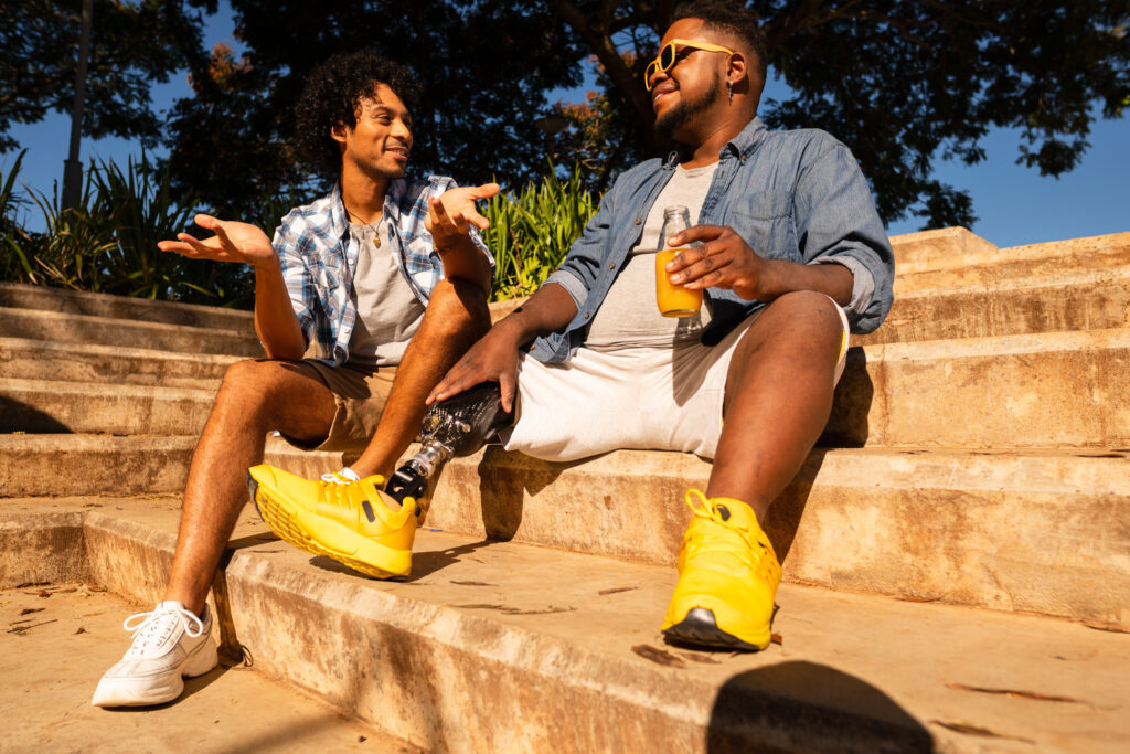 Two males talking while sitting on steps outside.