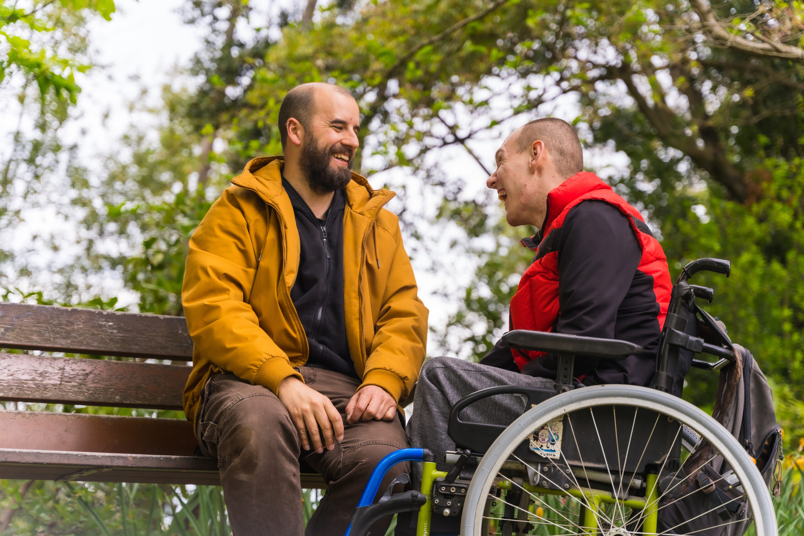 A man on a bench talking to another man in a wheelchair