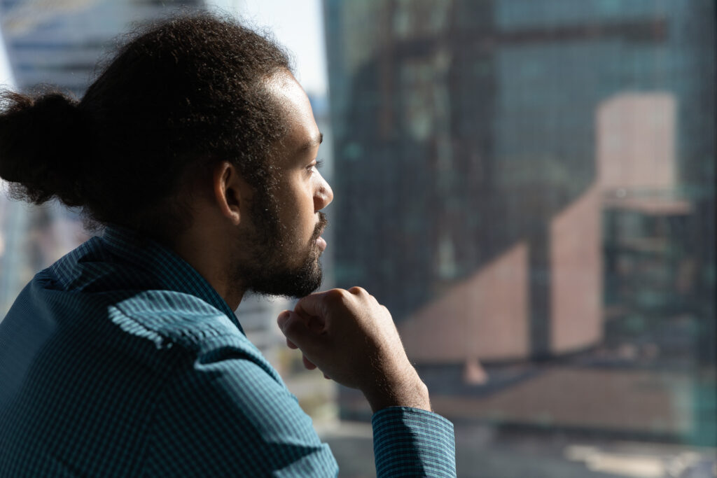 Man looking out a window thinking.