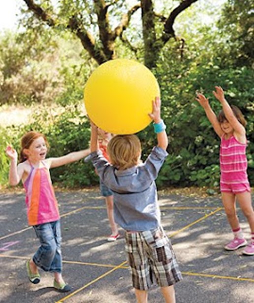Children in a circle tossing a large ball back and forth.