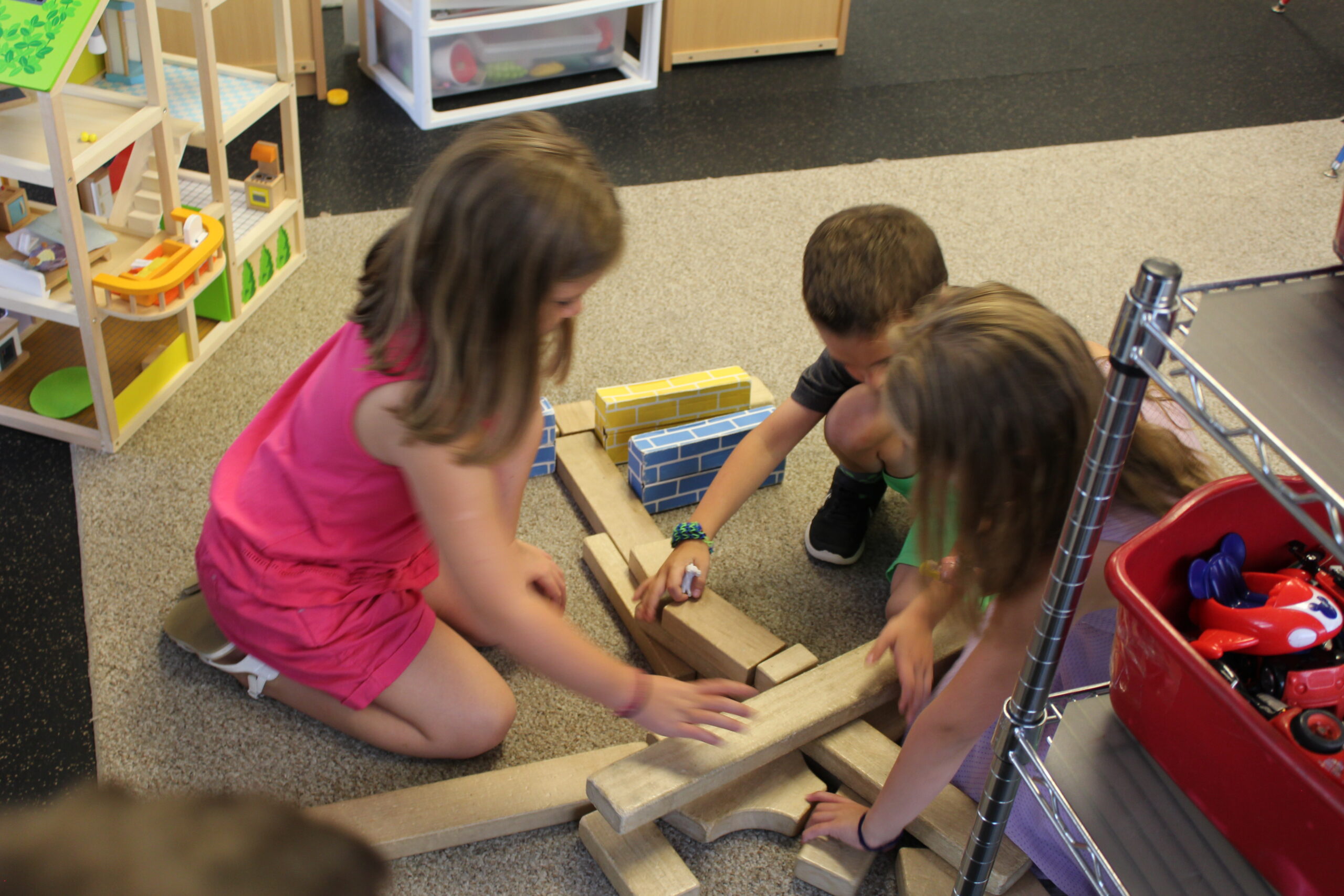 Group of school age children building with blocks on the floor.