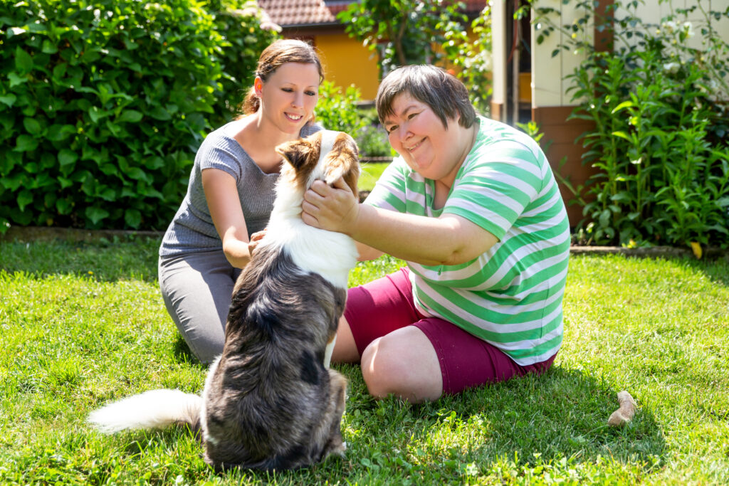 Two women petting a dog outside.