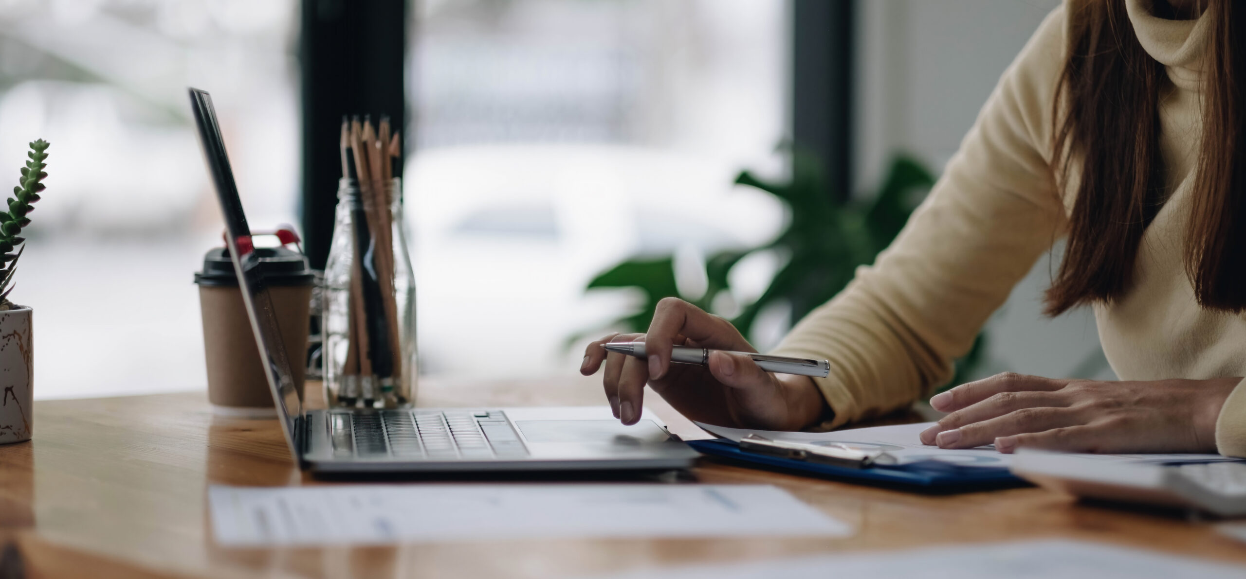 A person sits at a desk with an open laptop before them.